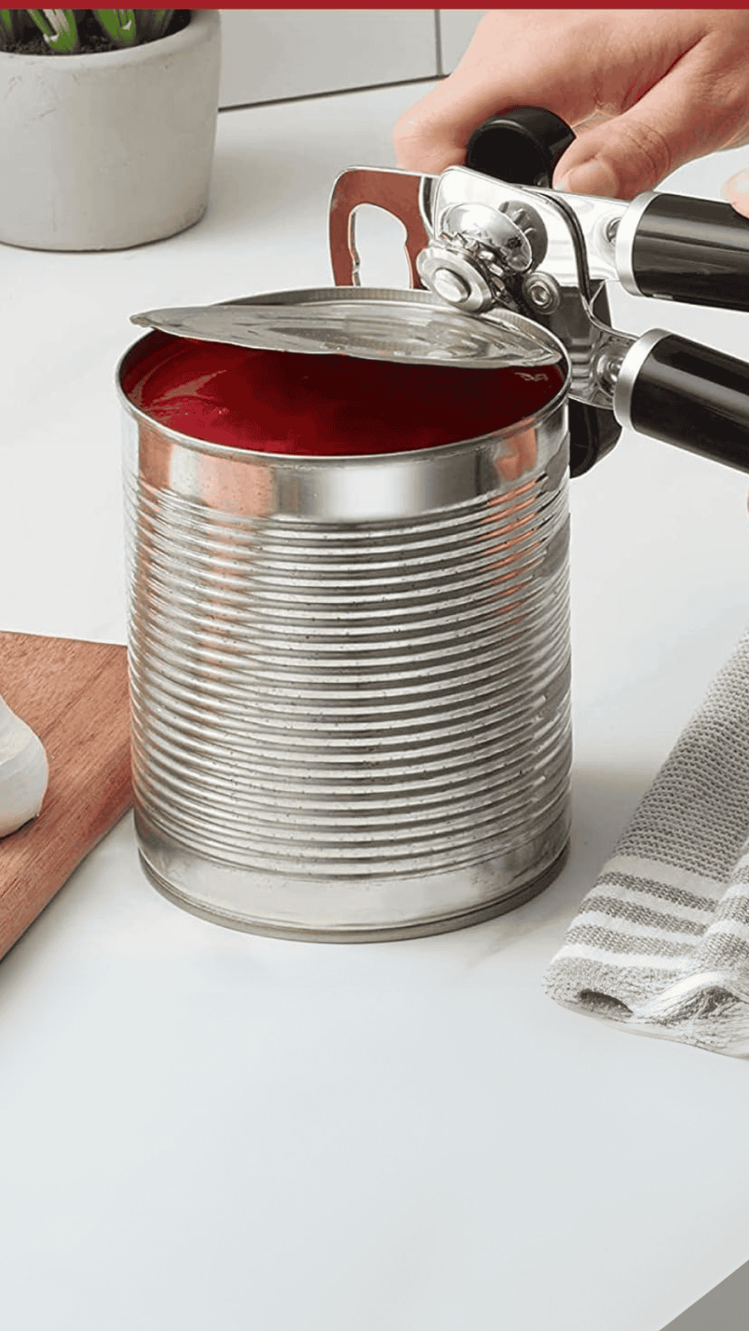 una mano con un abrelatas KItchenAid abriendo una lata