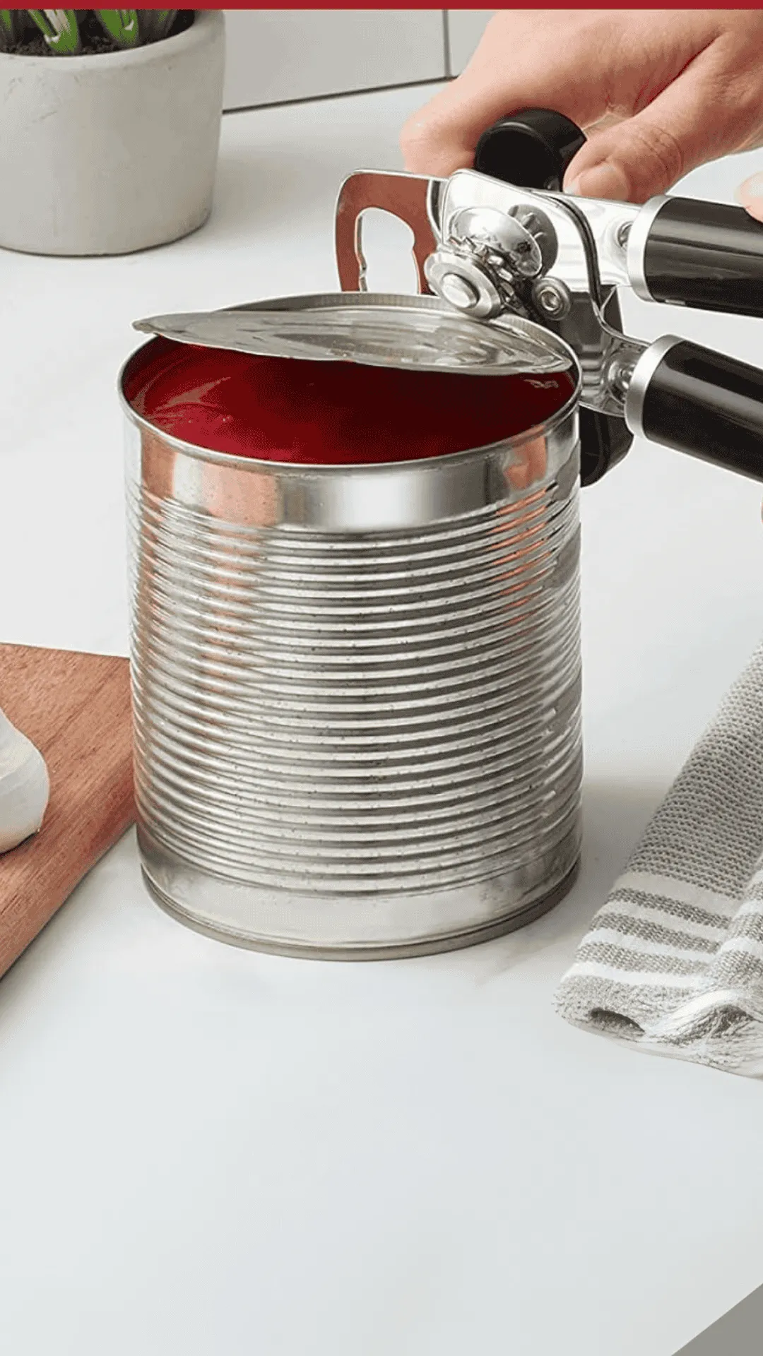 una mano con un abrelatas KItchenAid abriendo una lata