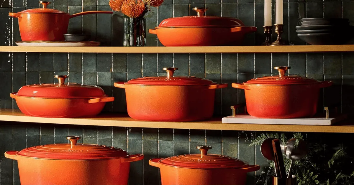Varias piezas de Le Creuset Línea Centenario sobre tres estanterias