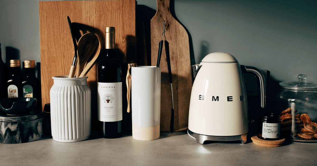 Una Pava Eléctrica Smeg sobre una mesada con otros utensilios y botellas