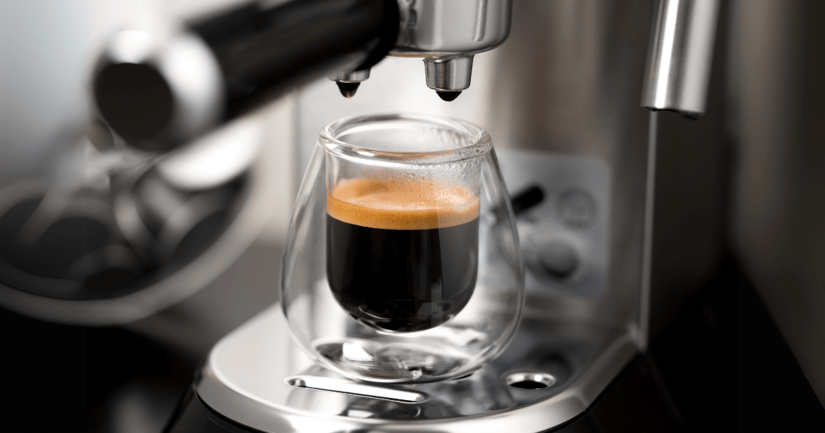 Una taza de café de vidrio de doble pared en unas máquinas de café espresso
