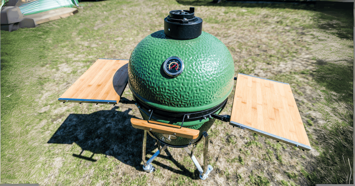Kamado color verde con mesa de bambú sobre el césped