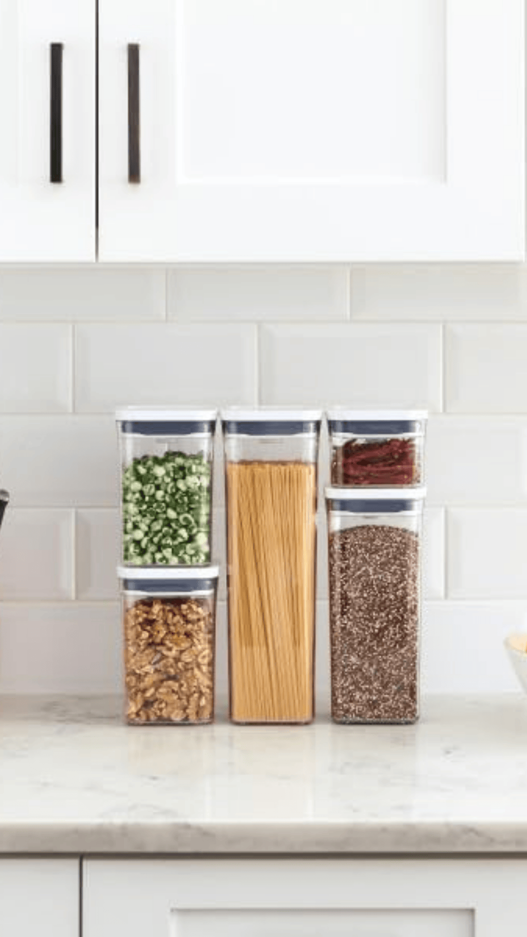 Cinco frascos OXO pop de diferentes tamaños apilados en una mesada con varios productos en su interior
