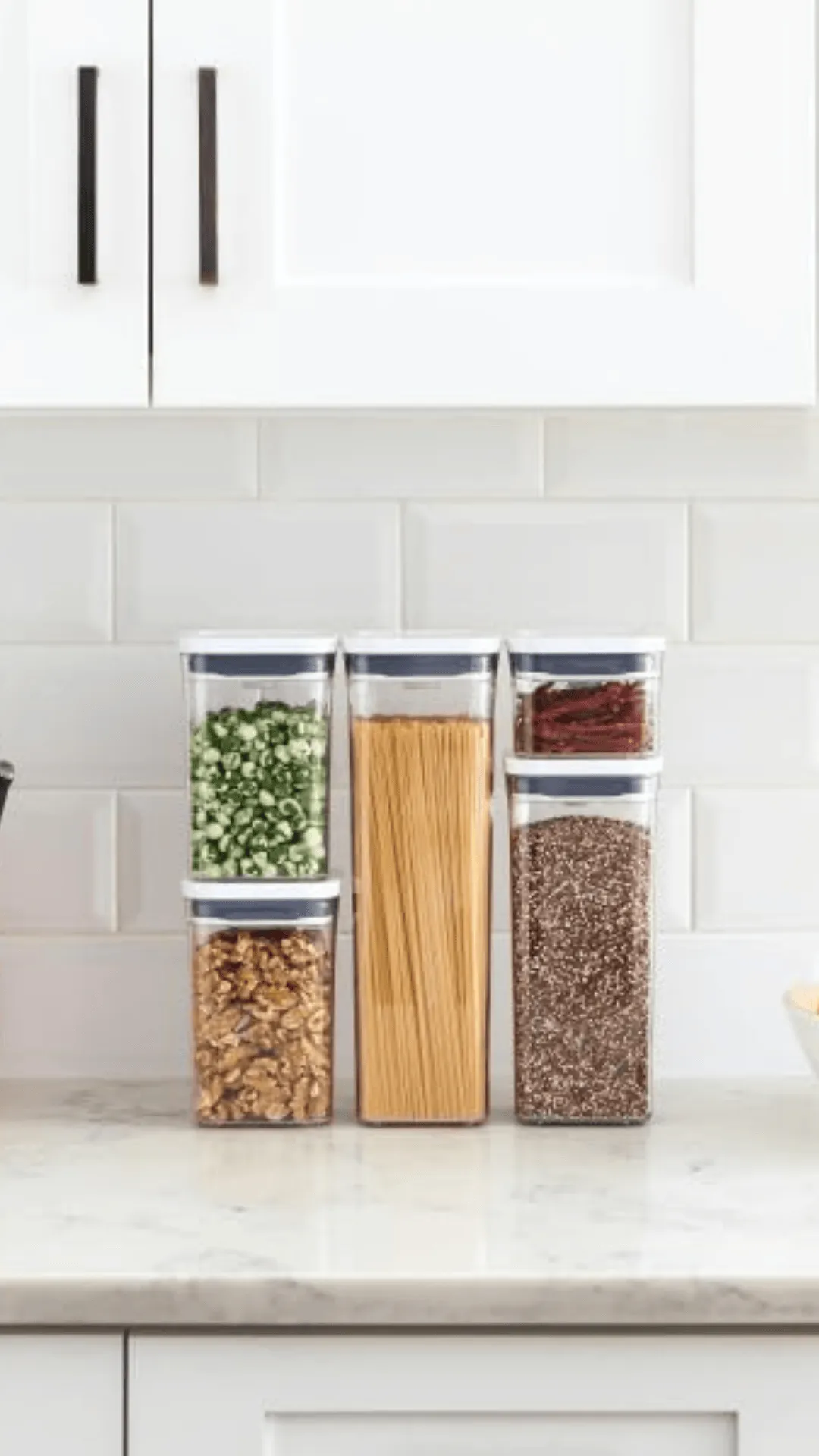 Cinco frascos OXO pop de diferentes tamaños apilados en una mesada con varios productos en su interior